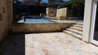 Limestone Paving and Steps on a Frameless Glass Fence Pool