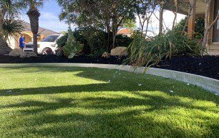 Close up view of artificial grass surrounded by green garden plants